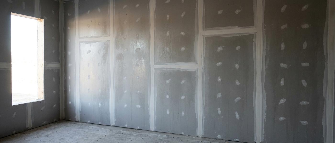 Freshly taped drywall seams bedded under white joint compound on an interior wall